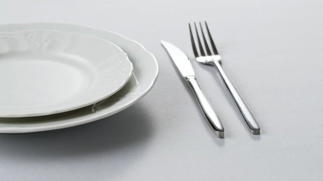 Fancy restaurant, waiter Elegant table setting with white square plate and silverware, arranged for sophisticated dining
