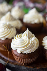 Sweet dessert for breakfast: chocolate cupcakes with vanilla cream on a gray background. Close-up. Vertical photo