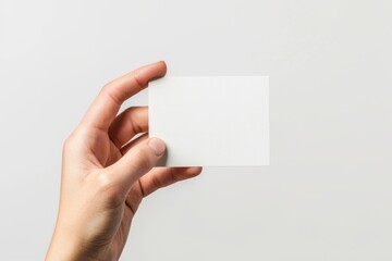 Obraz premium A hand holding up an empty business card against a white background in a close-up, high resolution 