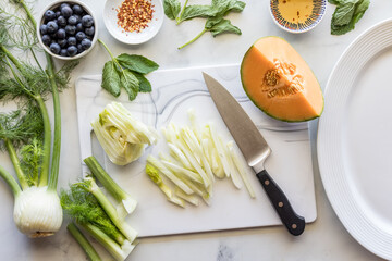 Above view of ingredients for preparing a fennel, melon and blueberry salad.