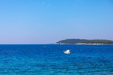 Beautiful seascape with blue sea and white boat in Croatia. Boat is floating in the sea with a yellow buoy in the water. The sky is clear and blue, and the water is calm