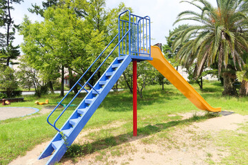 colourful slide with staircase taken in a park on a sunny day with grass field