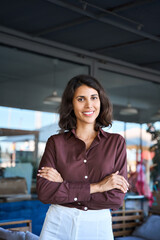 Vertical portrait of beautiful successful confident hispanic young business woman looking proud at camera. Smiling middle age latin female lady businesswoman, customer standing hands crossed outdoors