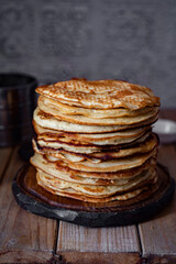 Delicious breakfast for the whole family: a stack of sweet pancakes on a wooden table. Vertical photo. Close-up