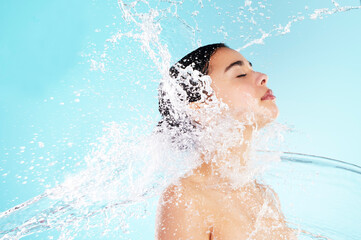 Cleaning, hygiene and water splash with woman in studio on blue background for skincare. Beauty, hydration and wellness with satisfied or wet model in spa shower for calm, relaxation and washing