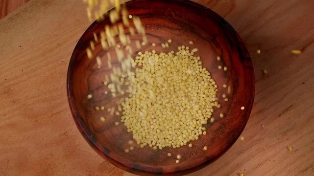 Millet falling into a bowl, healthy eating. Dieting, quinoa grain prepared for cooking