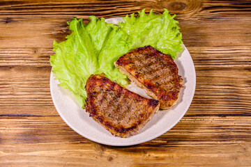 Plate with roasted steaks and rosemary twigs on a wooden table