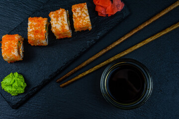 Sushi roll philadelphia with salmon, rice, cheese, cucumber, avocado and caviar on a slate board. Japanese food. Top view