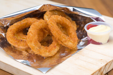 Crispy Battered Onion Rings Served with Ketchup and Mayonnaise on a Restaurant Table