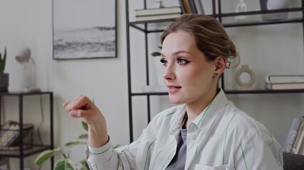 Medium close-up of young Caucasian female teacher with hearing disability sitting in classroom, articulating and demonstrating simple everyday words Hello, deaf, yes, no, sorry, in ASL at lesson