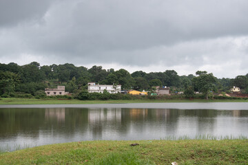 tranquil water of netarhat lake, jharkhand, india with scattered small village house and green surrounded trees