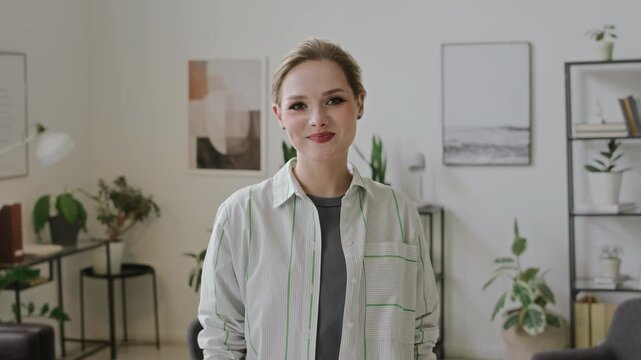 Medium POV portrait of smiling deaf-mute young Caucasian woman demonstrating phrase, Hello, I like you, in American sign language, looking at camera and smiling