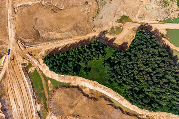 Aerial view of a preserved forest area in the middle of a huge sand quarry