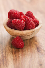 fresh raspberries in wood bowl on table with copy space