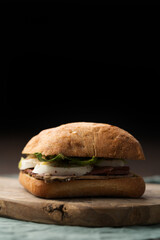 Roast beef and mozzarella sandwich with ciabatta bun on olive board