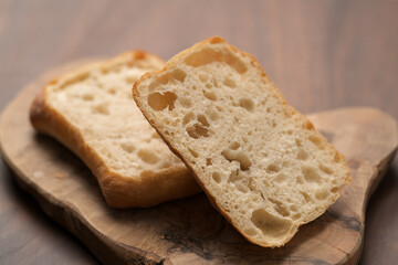 sliced ciabatta bun on wood board closeup