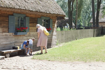 Rodzina. Mama ubierająca dziecko. Przed domem. Polska - Mazury - Warmia. © Rafa