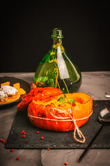 Baked pumpkin with vegetable puree soup with chanterelles and mint on a black mica board with herbal tincture in a green bottle. Elegant presentation of the dish. Vertical photo