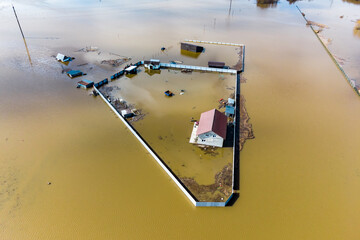 Flooded farm plot with a house in the middle of a field, spring river flood, aerial view