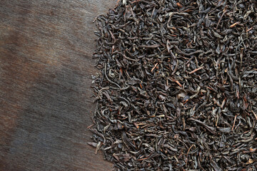 Long black tea on a dark wooden background. Top view of dried tea leaves. Tea composition. Ingredients for a hot drink, close-up