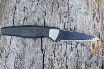one small old black knife lies on a gray wooden table
