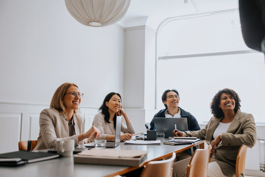 Happy male and female business professionals sitting in business meeting at office