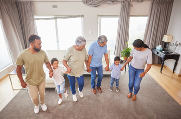 Family, dance and fun in home while holding hands for bonding, support or people playing game. Grandparents, parents and children in living room for birthday party, celebration or learning with music