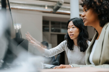 Businesswoman explaining while sitting with female coworker at office