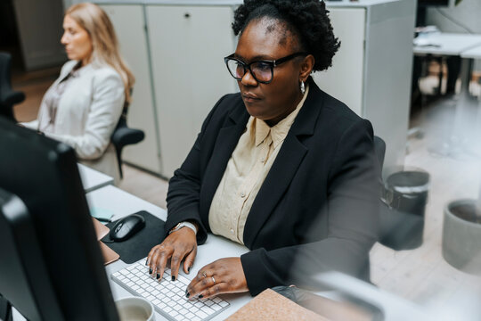 High angle view of focused businesswoman typing on keyboard while sitting and working in office