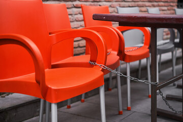 red plastic chairs chained to table, protection against theft, closed street cafe