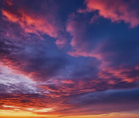 Obraz premium Spektakulärer Sonnenuntergang mit dramatischen Wolken in leuchtenden Rot-, Pink- und Violetttönen, die den Himmel in einer atemberaubenden Farbenpracht erstrahlen lassen