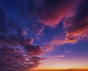 Obraz premium Wunderschöner Sonnenuntergang mit intensiv leuchtenden Wolken in tiefem Violett und zartem Pink, die den Himmel in warmen, faszinierenden Farben erstrahlen lassen