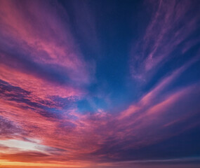 Fototapeta premium Spektakulärer Sonnenuntergang mit dramatischen Wolken, die in intensiven Pink- und Violetttönen den Himmel erleuchten und eine bezaubernde Abendstimmung schaffen