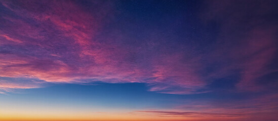 Fototapeta premium Himmel bei Sonnenuntergang mit intensiven Rosa- und Violetttönen, die den klaren Himmel und die Wolken in eine traumhafte und beruhigende Atmosphäre tauchen