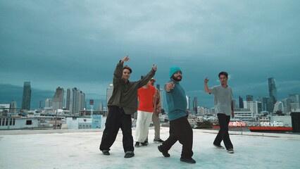 Hispanic hipster dancing surrounded by multicultural friend at city view with blue sky. Group of street dancer performing at rooftop. Active, fun, happy atmosphere. Outdoor sport 2024. Hiphop.