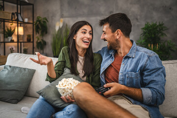 adult couple watch movie, series on television and eat popcorn at home