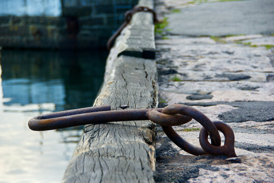 Rusty mooring ring with grappling iron on a stone quay in a harbour on the danish island Bornholm. 