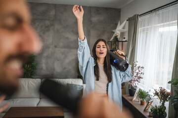 adult young woman dance with loudspeaker on karaoke party at home