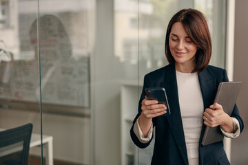 Professional businesswoman focused on using her smartphone in a modern office setting