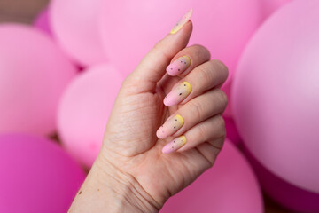 a woman with yellow nails that has a pink background