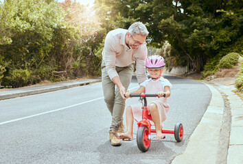 Father, child and learn to ride bicycle for development, coordination exercise and trust on road. Dad, bonding and teaching young girl in nature for cycling, training wheels and support in lesson