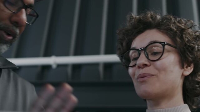 Close-up shot of face of mature Asian car mechanic describing necessary maintenance work to smiling Caucasian female customer, offering discount, happy woman agreeing