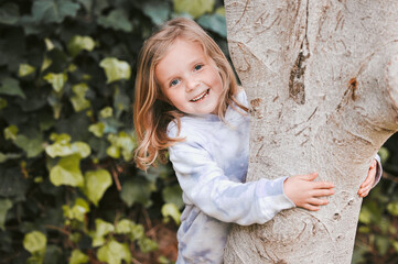 Park, kid or girl in portrait with smile, playful and happiness on vacation holiday for summer outdoor. Garden, female child and balance by tree for growth, childhood development and confidence