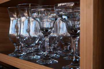 Wine glasses on a wooden shelf in a restaurant. Empty wine glasses on wooden shelf, closeup.