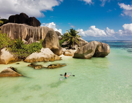Young woman kayaking during summer day at La Digue island.