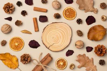 Autumn composition. Podium, pedestal, presentation empty mockup with leaves, nut, cones, dried fruits, cinnamon sticks on beige background. Top view, flat lay