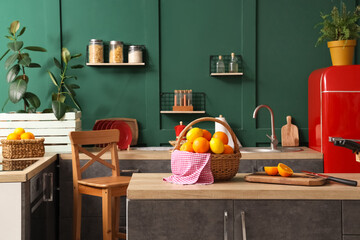 Wicker basket with citruses on counter in green kitchen