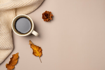 Cup of coffee, scarf, leaves and cone on beige background. Autumn leisure concept. Flat lay, top...