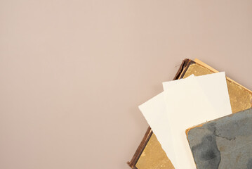 Vintage books and paper blank sheet on beige background. Top view, copy space