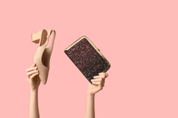 Female hands with bag and heeled shoe on pink background